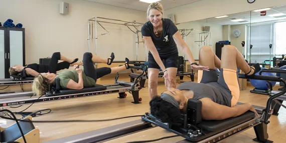 Personal trainer working with someone on pilates reformer