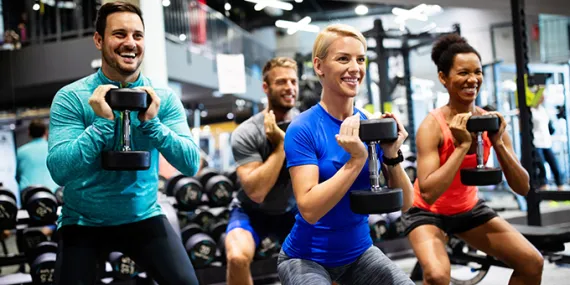 four people lifting weights in a group class