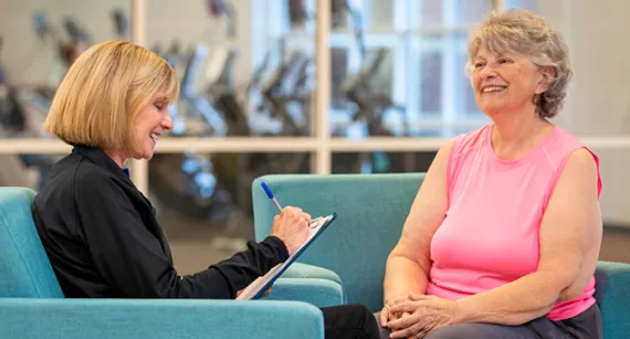 Two women chatting in the lobby with a clip board