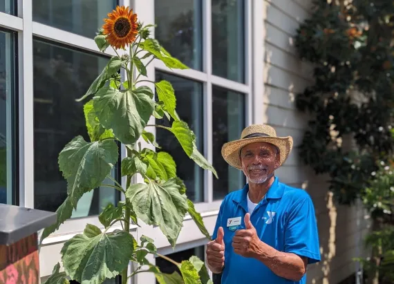 Facility staff in front of sunflower.